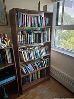 Full view of brown five-shelf bookcase against wall