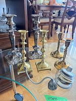 Group of candlesticks, snuffer, coaster stack on glass table