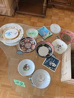 Assorted vintage plates, bowls and trivets on glass table