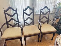 Three dark wood dining chairs aligned, showing overall design and upholstery