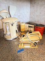 Group shot showing all items: Westinghouse can opener with utensils, Wiltshire electric knife, Sunbeam whisk, flour sifter tin, spice shaker