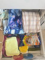 Drawer with folded patterned towels, microfiber cloths, Lysol wipes box, smile-face sponge