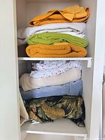 Shelf showing multiple folded linens in various colors and patterns