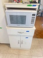 Front view of cabinet with microwave on upper shelf