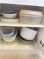 Overall view of cabinet shelves showing stacked baking dishes, storage container and nested plastic bowls