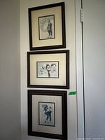 Three framed clown paintings hung vertically on wall