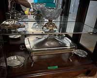 Group shot showing all silver-plated pieces and crystal compote in cabinet