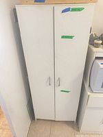 front view of white two-door cabinet with metal handles