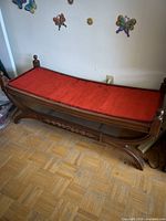 Full view of wooden bench with red cushion