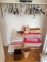 Closet showing hangers on rail, wicker baskets, plastic totes and bins stacked below