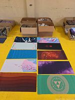 Overview of multiple unrolled desk mats laid out and cartons filled with rolled mats behind