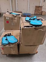 Full pallet with multiple crushed cartons holding blue/teal tote bags on top