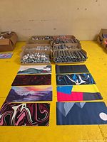 Pallet boxes of rolled shrink-wrapped mouse pads and several unrolled showing assorted prints