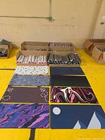 boxes of rolled desk mats and eight sample mats laid out showing assorted designs