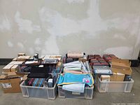 Full view of three large bins filled with boxed accessories, desk mats, and travel cases