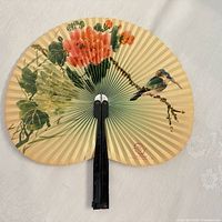 Full view of folded-out hand fan showing bird and floral artwork, black handle visible