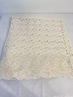 Folded ivory crocheted tablecloth on surface