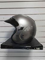 Left side profile of silver open-face helmet on shelf