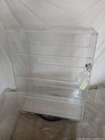 Front view of clear acrylic 5-tier swivel display case showing shelves and lock