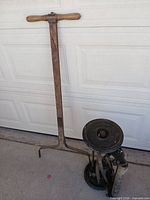 Full view of detached wooden handle and reel assembly leaning against garage door