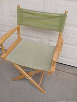 Front view of folding wooden director’s chair with green canvas seat and backrest