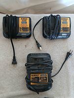 Three DEWALT chargers, two DCB112 and one DCB101, cords wrapped