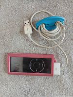 iPod Nano with pink case connected to 30-pin cable wound in blue organizer
