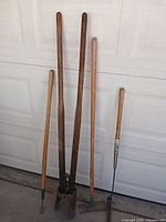 All four long-handled tools leaning against door