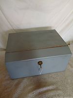 Front view of gray metal lockbox, lid closed
