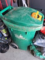 Full view of green wheeled trash cart with lid, logo, wheels and latch visible