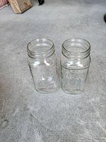 Two clear Atlas Mason quart jars standing upright on floor