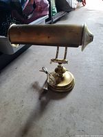 Full view of brass piano/desk lamp showing shade, arms, base, and power cord