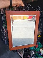 Front view of rectangular wood-framed mirror showing black metal scroll accents and reflective glass