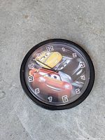 Front view of Disney Pixar Cars wall clock showing design, numerals, frame condition