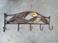 Front view of metal coat rack showing floral motif and five hooks