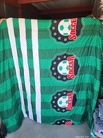 Full view of green and white striped soccer comforter held up for scale