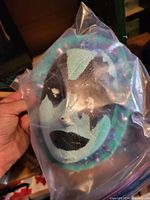 Front view of teal and black glittered decorative mask in plastic bag