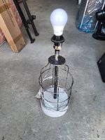 Full view of cage-style metal and glass table lamp with LED bulb installed