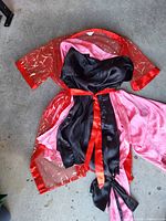 Full view of robe laid flat showing red mesh with gold pattern, pink satin panels, black inner panel and red belt