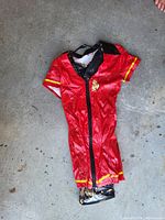 Full view of red vinyl firefighter costume dress laid flat