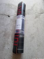 Rolled Lululemon yoga mat in shrink wrap showing black exterior with red edge