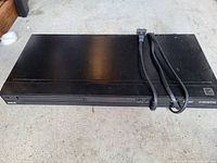 Top view of black DVD player with attached power cable showing overall condition