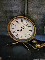 Front view of metal bird motif tabletop mantel clock showing face and bird detail