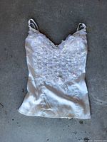 Front view of white satin camisole slip showing lace straps, ruffled lace bodice and overall condition