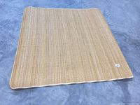 Full view of square natural fiber rug on concrete floor