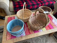 All four baskets on coffee table: three wicker, one blue wood-slat