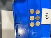 Six coins laid out in two columns of three on blue plastic surface