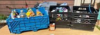 Three crates on table filled with assorted aerosol and liquid cleaning/maintenance products; crates not included.