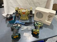Group view showing both impact drivers, bench grinder, charger with battery pack, space heater, rivet gun and hardware
