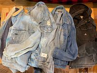 Four jackets laid out: three denim, one Carhartt hooded work jacket